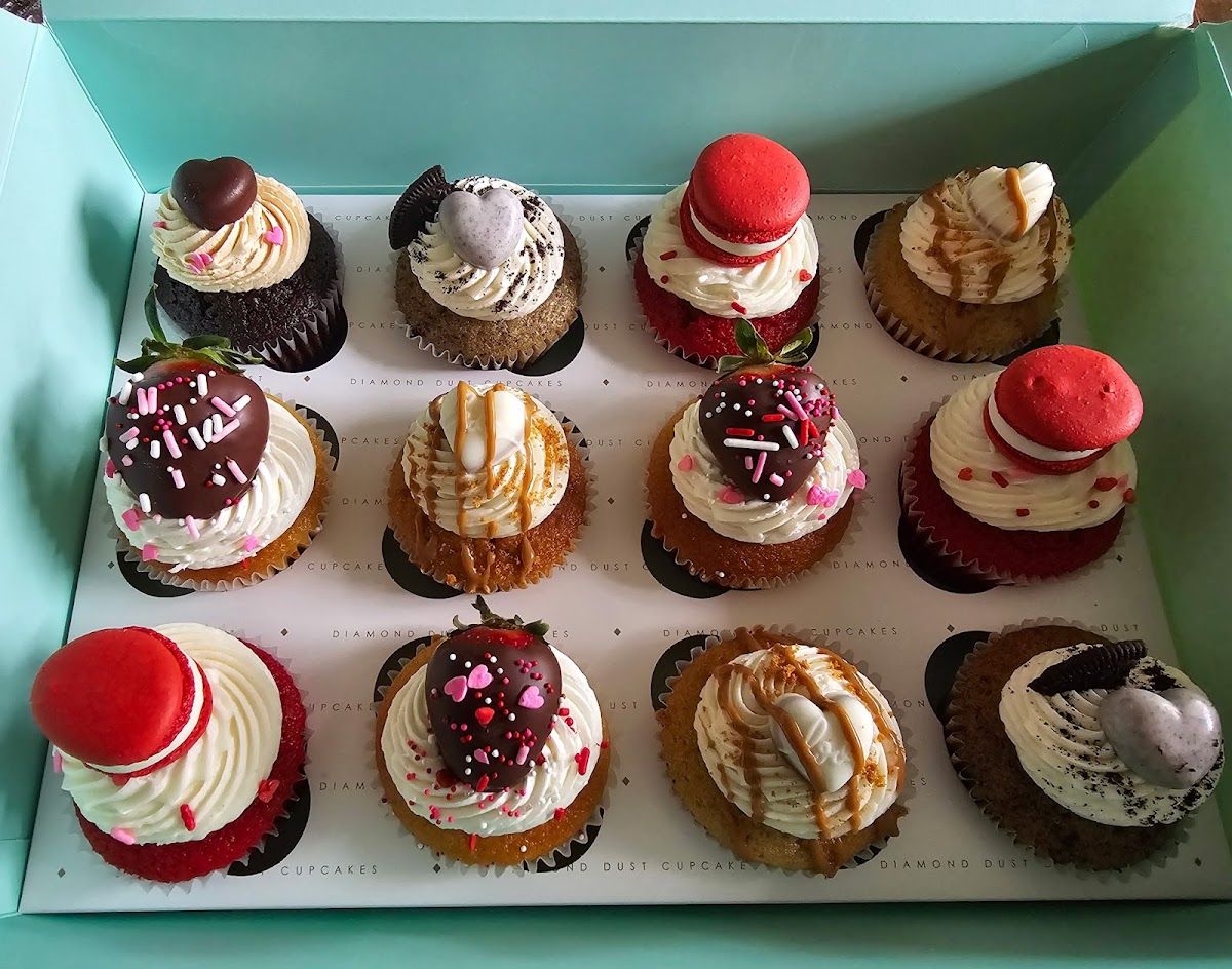 A box of a dozen assorted gourmet cupcakes with decorated tops
