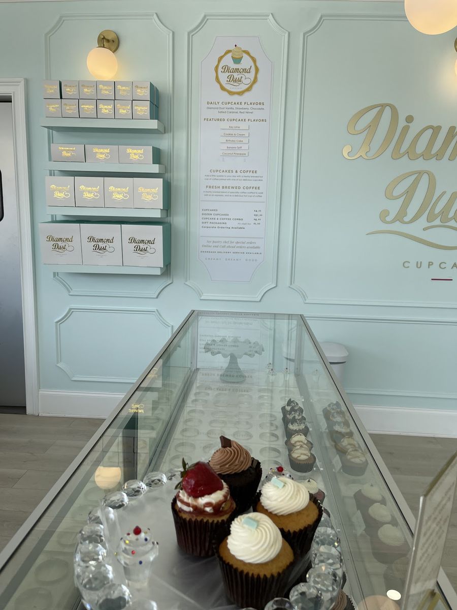 The mint-and-gold interior of Diamond Dust, with the flavor menu and glass cupcake case